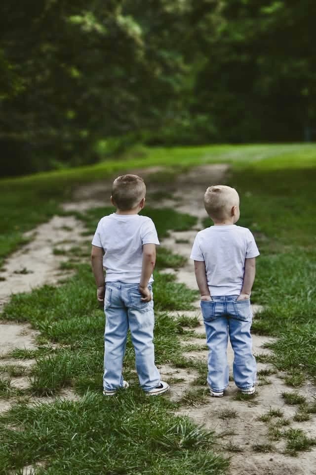Twin brothers standing side by side on a country path