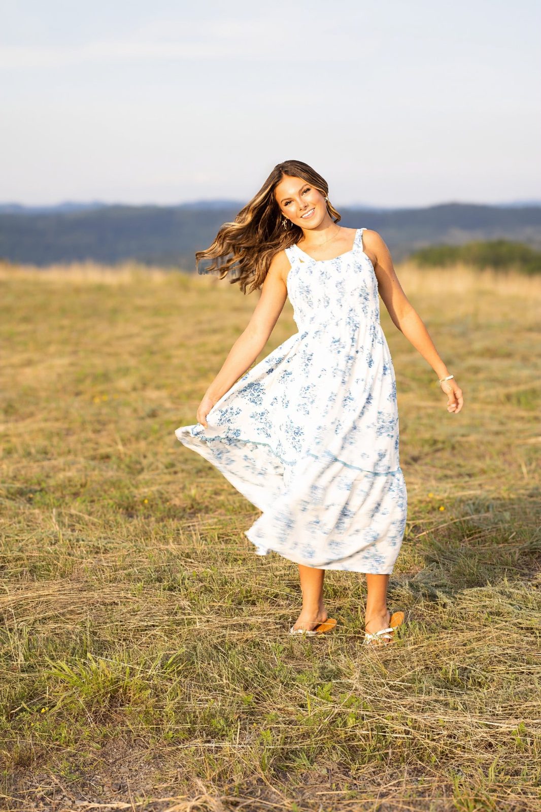 A senior in a flowing dress in a sunlit field