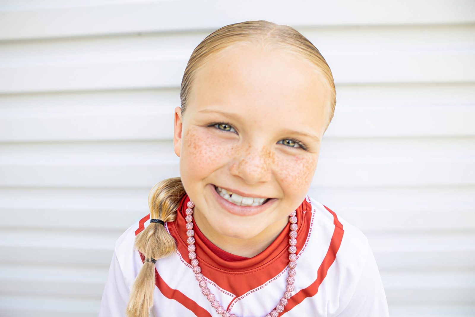 A young softball player smiling in her uniform